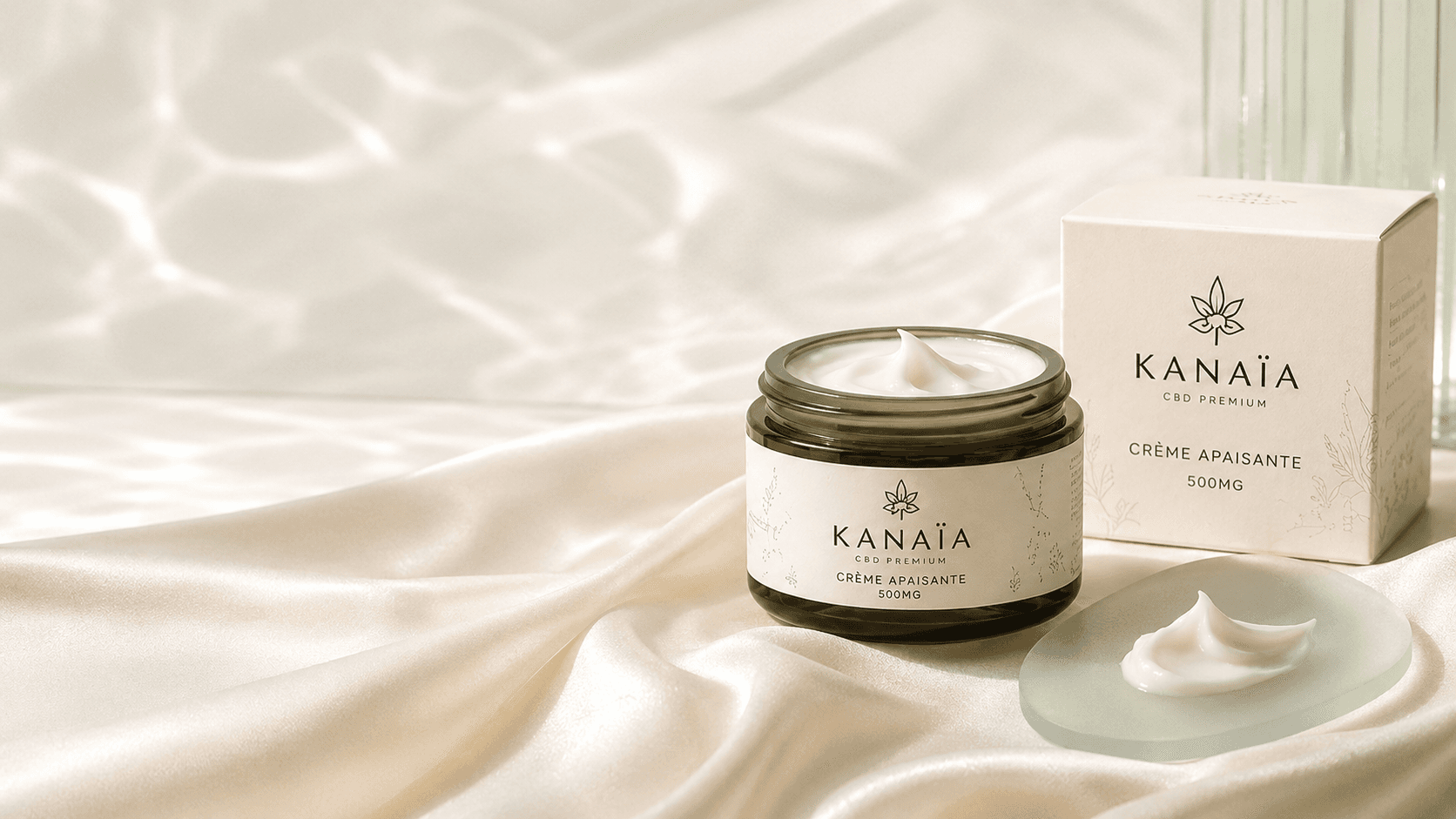 Le pot de crème apaisante KANAÏA ouvert sur un drapé de soie ivoire, noisette de texture crémeuse