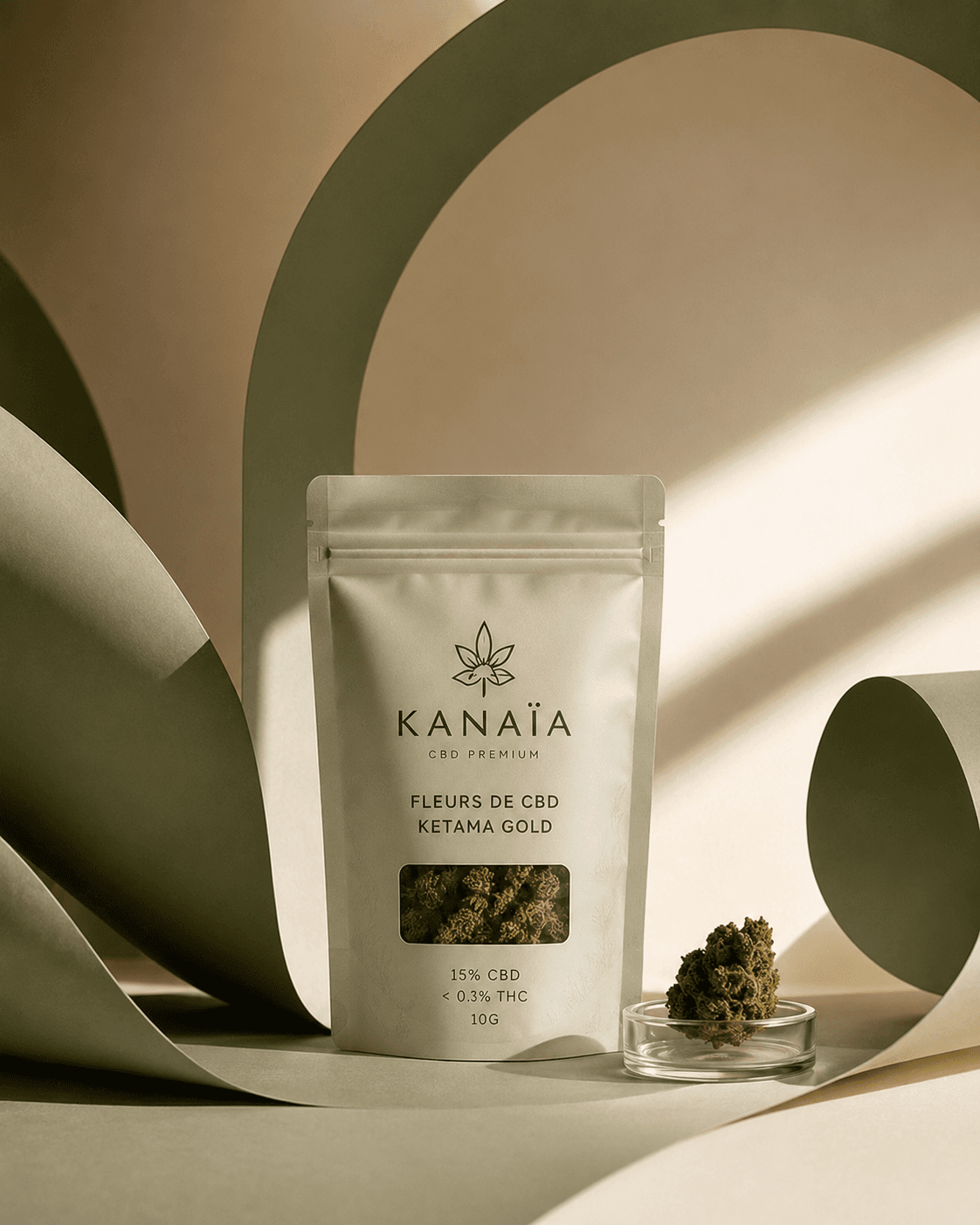 Sachet de fleurs de CBD KANAÏA Ketama Gold entre des volutes de papier sauge, lumière dorée